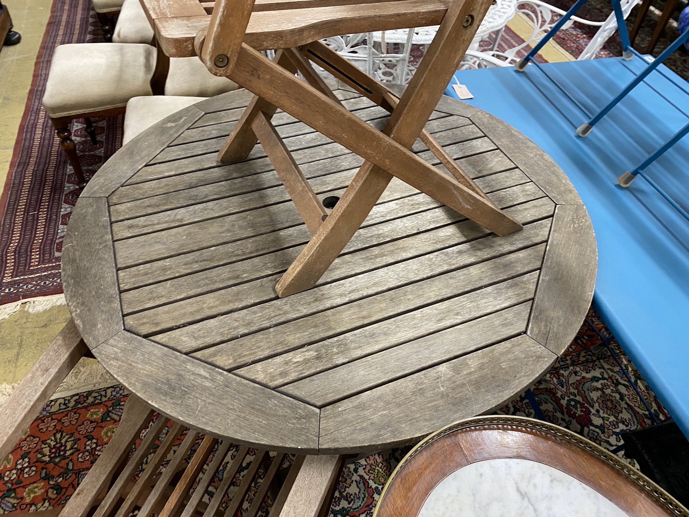 A circular weathered teak folding garden table, diameter 100cm, height 73cm and two elbow chairs